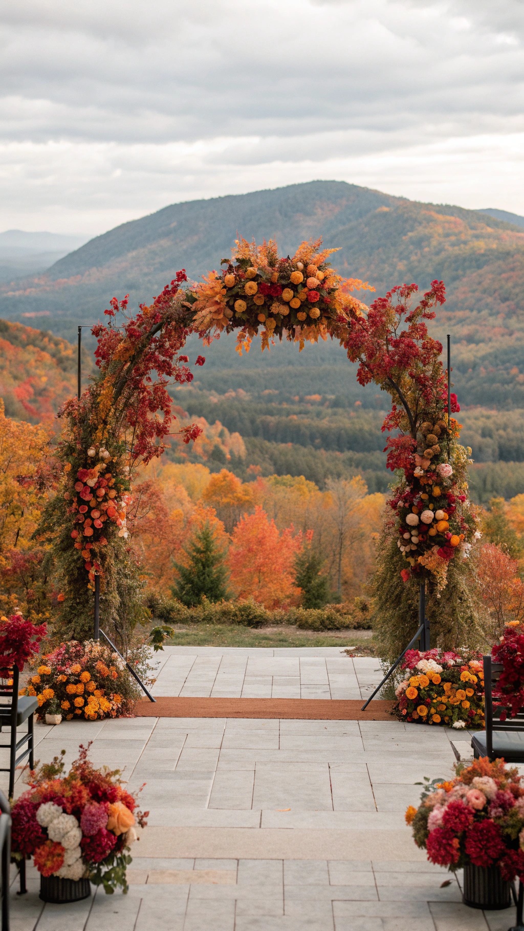 Ceremony backdrop featuring an arch with fall foliage and flowers, set against a scenic mountain view.