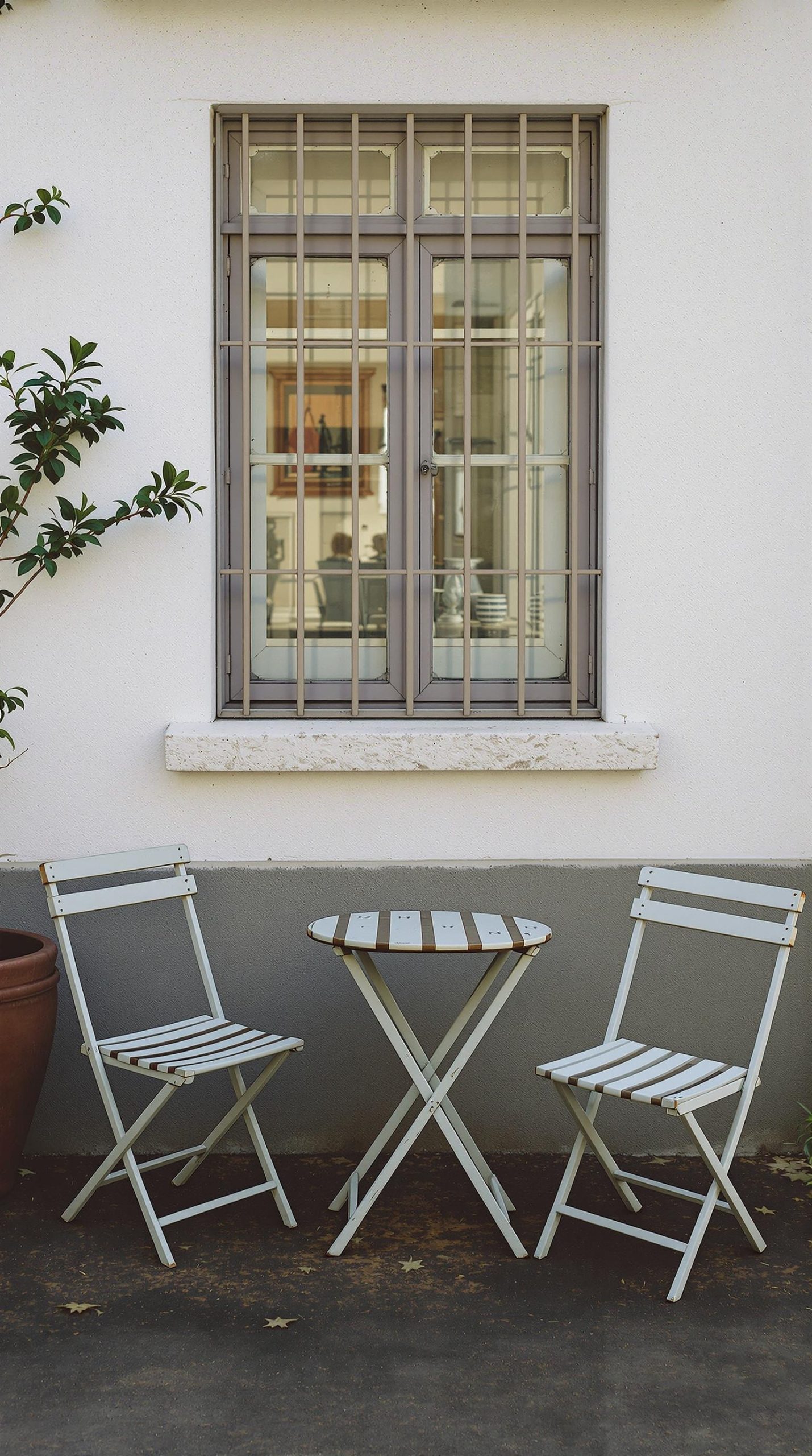 A pair of vintage folding chairs and a small round table on a patio.